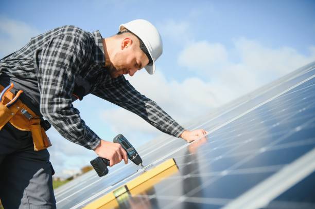 istock Portrait of smiling confident engineer technician with electrical screwdriver, standing in front of unfinished high exterior solar panel photo voltaic system 1453841053