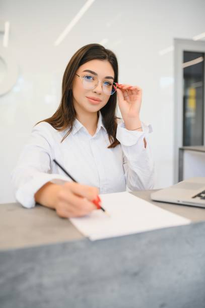 istock friendly young woman behind the reception desk administrator 1453841203