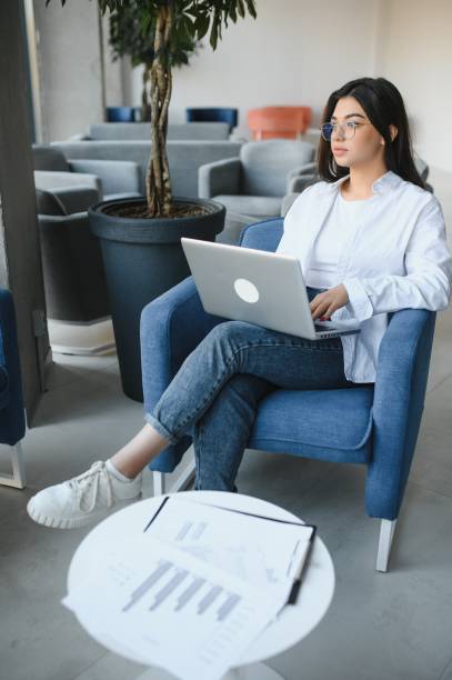 istock Young charming female freelancer using laptop computer for distance job while sitting in modern coffee shop interior, beautiful Caucasian woman working on net-book during morning breakfast in cafe bar 1453841321