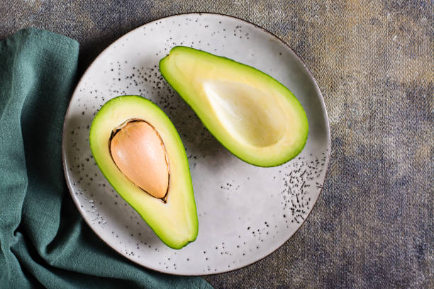 istock Cut in half fresh avocado on a plate on the table. Healthy food. Top view 1453841978