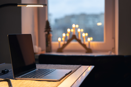Laptop on a table in a room interior with advent candles on a blurred background, copy space.