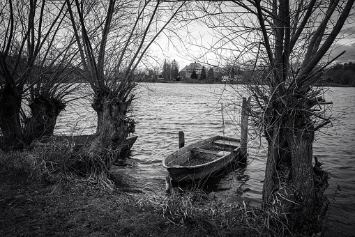 an old rowboat lies on the shore of a lake in black and white