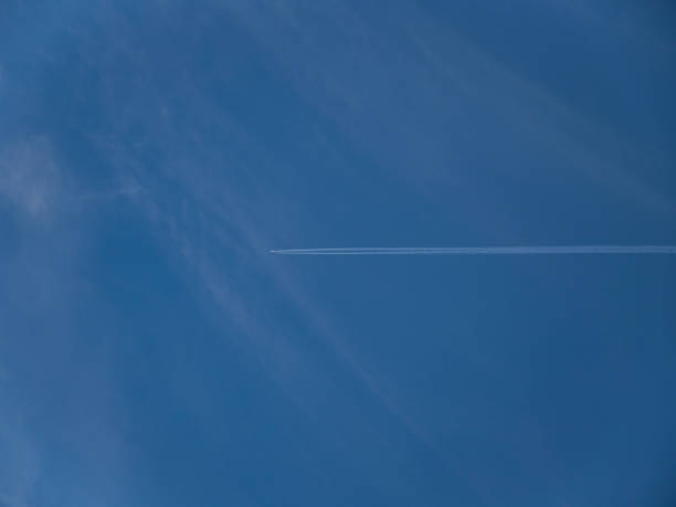 Airliner crossing blue sky horizontally leaving a vapor trail stock photo