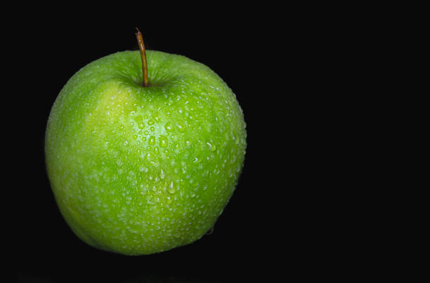 istock Green apple in water drops on a black background isolated. 1453848750