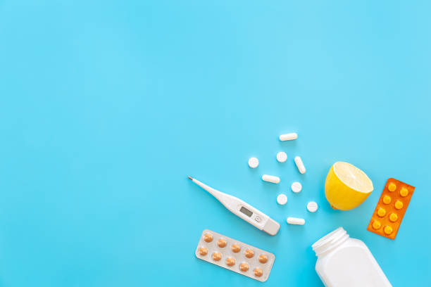 istock Blue background with pills, thermometer and lemon, flat lay. 1453849477
