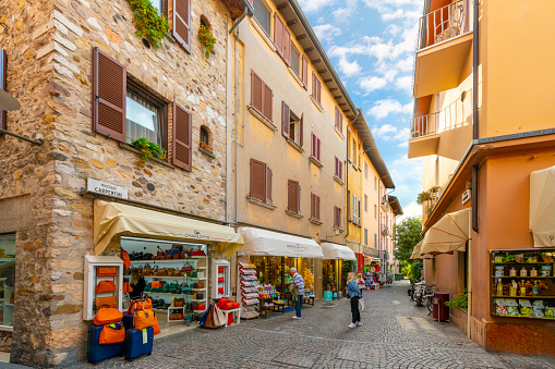 A picturesque narrow street or alley of shops in the colorful medieval center of the lakefront village of Sirmione, Italy, on the shores of Lake Garda.