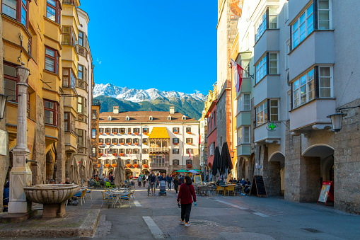 Snow capped mountains in early autumn above the historic Goldenes Dachl or Golden Roof in the medieval old town of Innsbruck, Austria, in the Austrian Alps.