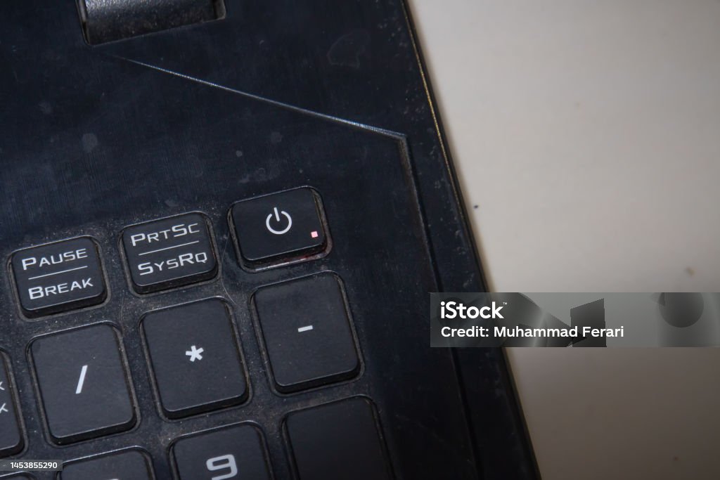 close up of a laptop with a lock and shutdown button Shutdown button in a black flat laptop with some noise of dust between the buttons 1980-1989 Stock Photo