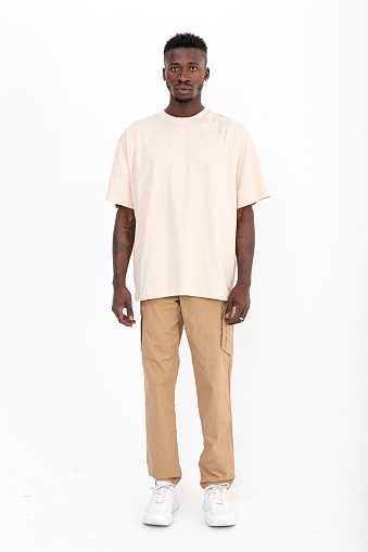 Black male model of African descent in front of white background wearing yellow t-shirt.