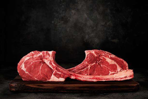 Raw tomahawk steak on wooden board stock photo