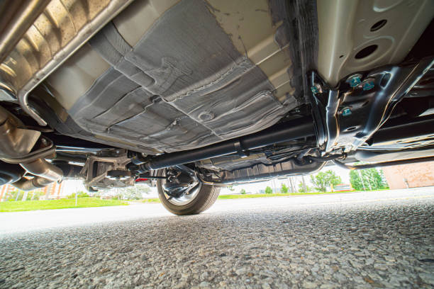 View of the car by auto mechanic from below. Automobile exhaust system and hoses. All wheel drive trance axle and gas tank with wheels suspension. Garage services, auto repair, road service. stock photo