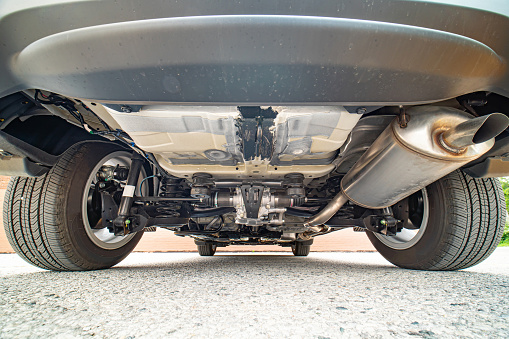 Auto mechanic view of bottom of the car. Rear differential axle wide angle, rear suspension system and components of exhaust system in passenger city car. All wheel drive system vehicle.