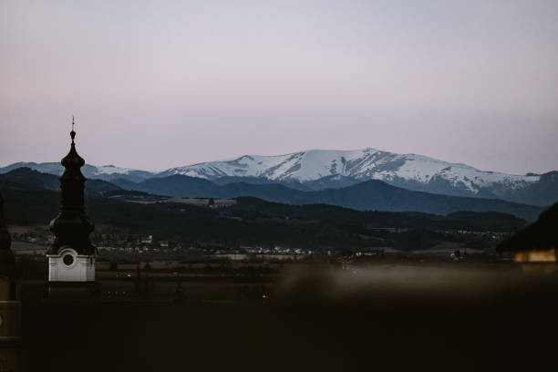 kirche mit teilweise verschneitem krizna-gipfel im hintergrund in der stadt zvolen während der blauen stunde - zvolen stock-fotos und bilder