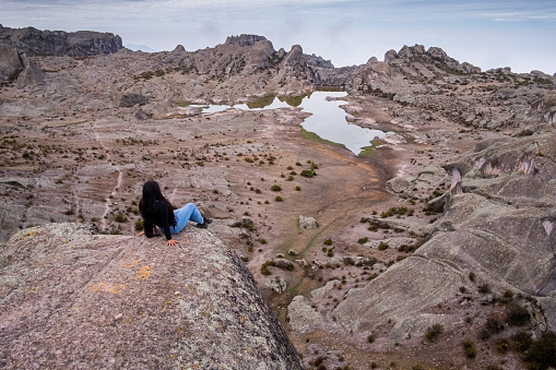 latina woman lying on a rock, with a lagoon and a valley of rocks in the background