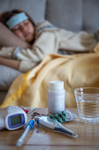 Sick influenza girl woman lying on the sofa And there is a fever meter and medicine on the table
