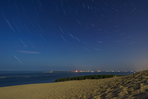 Long exposure of startrail at night over the huge natural sand formation Dune du Pilat in the moonlight, Arcachon, Nouvelle-Aquitaine, France
