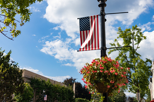 A hanging flower basket with an American flag along Greenwich Avenue in Downtown Greenwich Connecticut during the summer