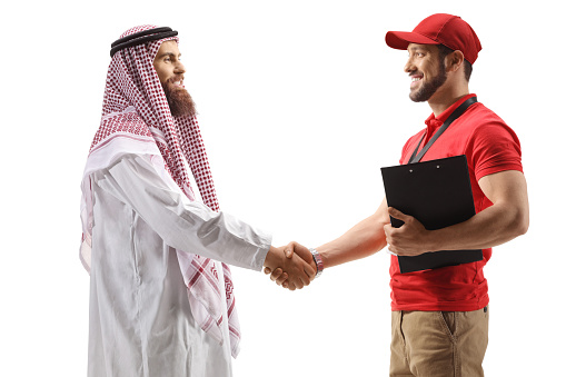 Profile shot of a delivery man shaking hands with a saudi arab man isolated on white background