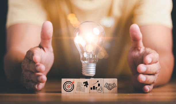 istock Light bulbs placed on wooden blocks and human hands on table ,target ideas and business strategies,through planning and teamwork To analyze and develop company performance from growth data to future 1453880109