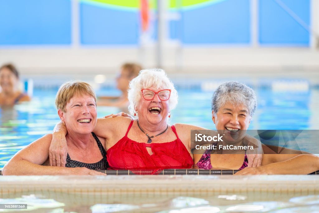 Senior Water Aerobics Class A group of happy seniors taking a water aerobics class at a community centre. The women use various pool equipment to exercise. Fun Stock Photo
