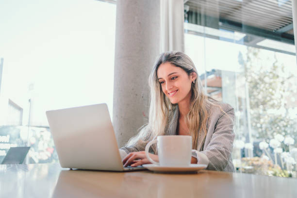 istock Attractive young business woman using computer, with mug of coffee in modern workplace. Millennial generation 1453884405