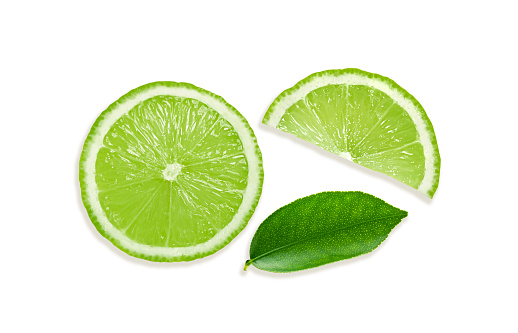 Fresh lime quarters falling into the cold water and splashing, isolated on white background. Splashing and bubbles visible.