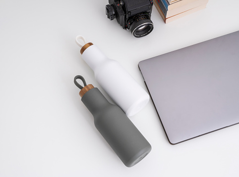 Modern desktop with laptop water bottles and camera