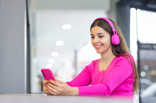 Young woman listening to music and using her phone