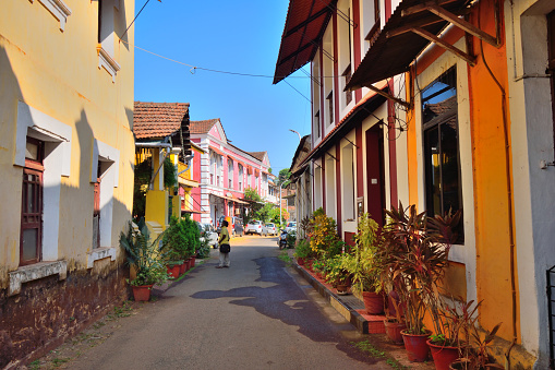 Panaji, India - January 23, 2019: A man walking on a narrow lane surrounded by colorful portuguese houses in Panjim, Goa.