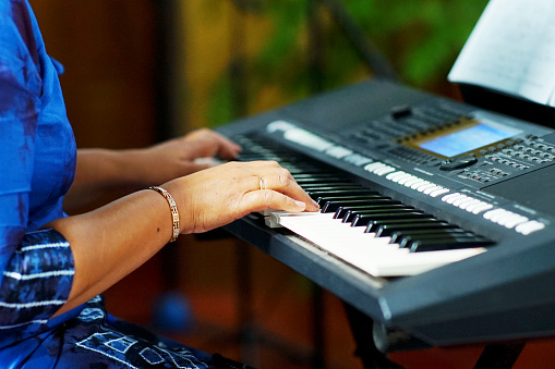closeup of an Asian mature woman playing the keyboard piano, side view