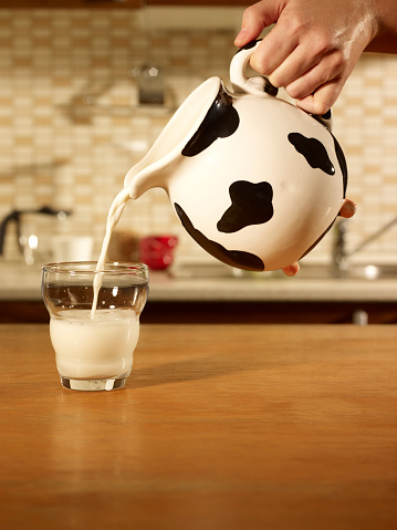 Woman hand Pouring a glass of milk