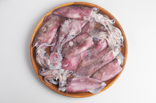 Fresh raw squids with ice and parsley on gray table, flat lay. On wooden background.