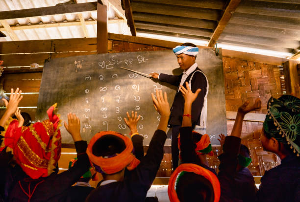 teacher and student with wearing hill tribe karen clothes study in class with karen alphabet present on blackboard and the student look like ask question during class in school. - hmong imagens e fotografias de stock