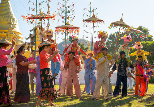 Group of Aisan people celebrating dance in front of golden pagoda in area of temple. It is name Poi Sang Long that relate to young novice buddhist monks.
