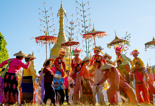 Group of Aisan people celebrate and enjoy dancing with Poy Sang Long Thai northern tradditional activities in front of golden pagoda in area of temple.