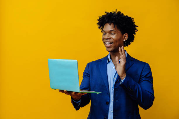istock Smiling young entrepreneur man waving at laptop screen 1453908866