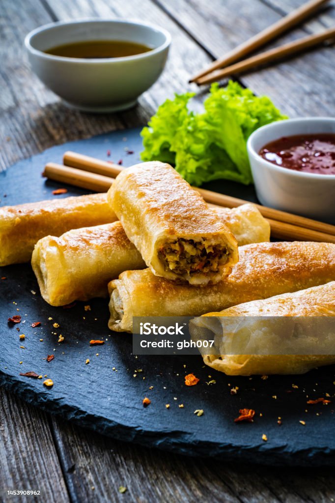 Spring rolls filled with meat and vegetables served with soy sauce on wooden table Spring Roll Stock Photo