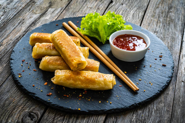 istock Spring rolls filled with meat and vegetables served with soy sauce on wooden table 1453908973