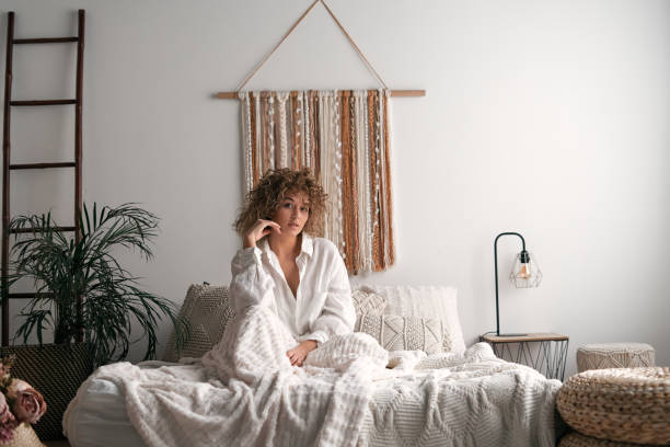 istock Young woman sitting on bed in morning 1453910951