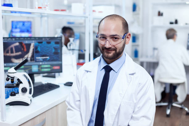 istock Pharmaceutical researcher sitting on stool looking at camera 1453913049