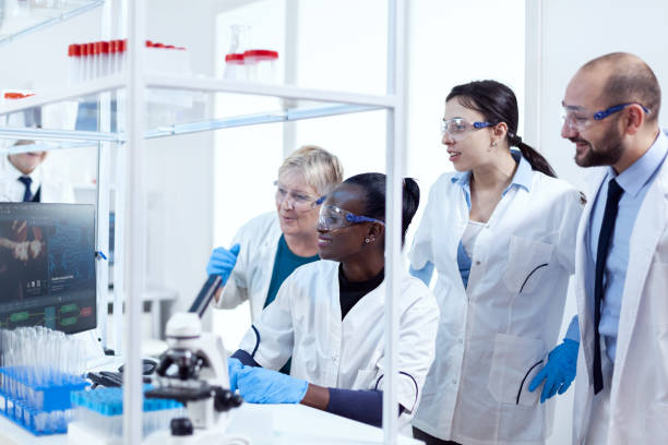 Group of multiethnic pharmacy scientists in lab coats working together Group of multiethnic pharmacy scientists in lab coats working together in modern facility. Black healthcare researcher in biochemistry laboratory wearing sterile equipment. Pharmacy Technicians Contribute stock pictures, royalty-free photos & images