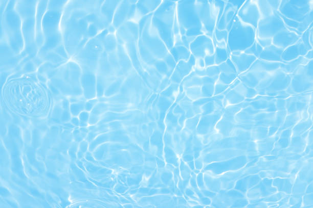istock Defocus blurred transparent blue colored clear calm water surface texture with splashes and bubbles. Trendy abstract nature background. Water waves in sunlight with caustics. Blue water spay shinning 1453913239