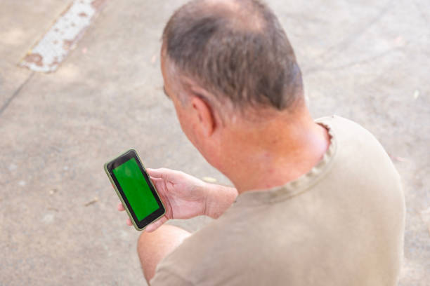 Middle aged man with a green screen on his phone