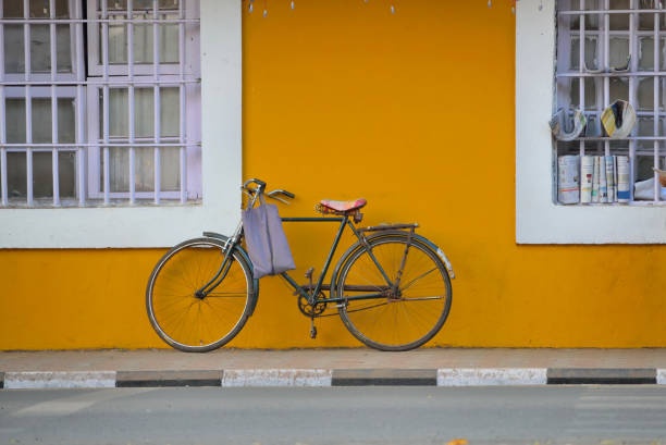 A cycle parked in front of a yellow coloured wall in Panaji, Goa.