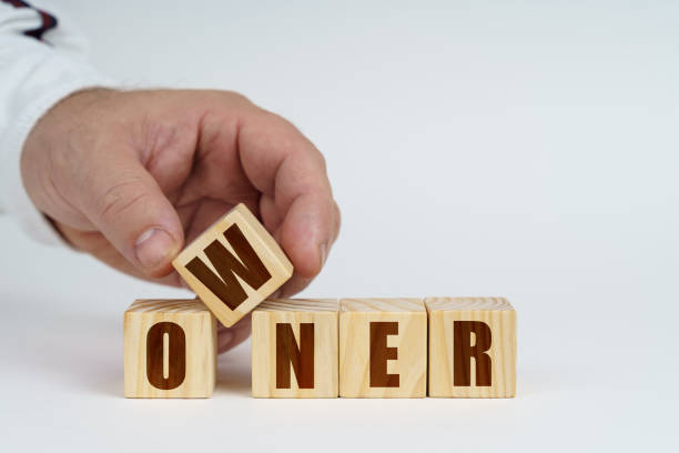 istock On a white surface, a man stacks cubes with the inscription - OWNER 1453917622