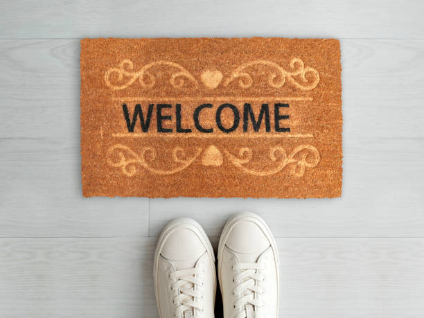 istock Designer Welcome Entry Doormat Placed on White Floor with White Shoes 1453918435