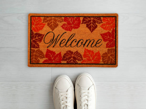 istock Designer Welcome Entry Doormat Placed on White Floor with White Shoes 1453920498