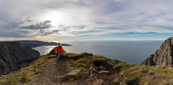Travelling woman at the North Cape framed by a breathtaking landscape and the midnight sun, Norway, Europe