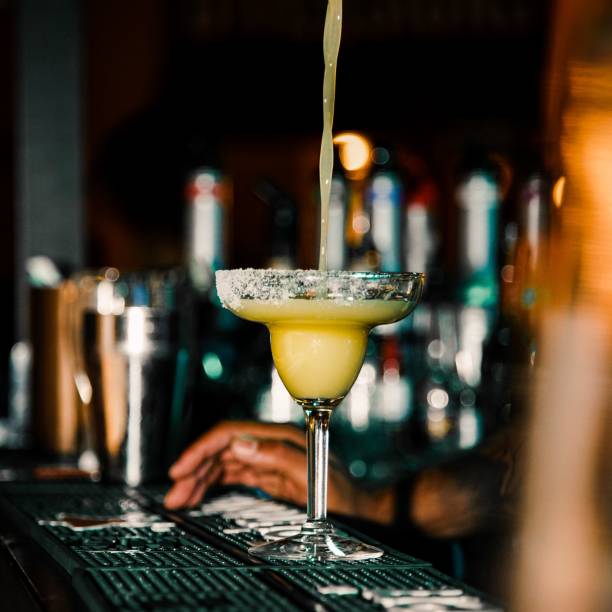 istock Cocktail on a table of a bar with a liquid being poured into it 1453925861