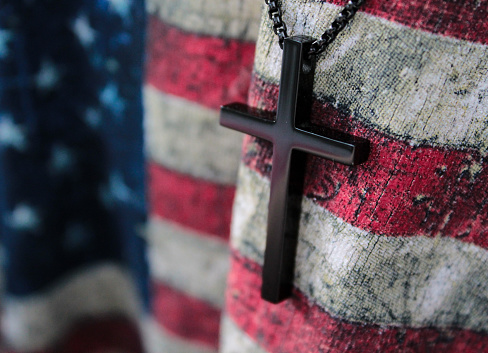 A small wooden cross and flag of USA. God save America